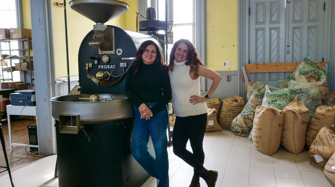 Maria and Val standing in front of the Las Chicas coffee grinder