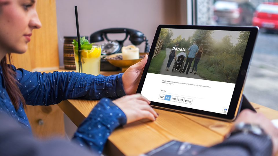 Two people browse the Sunshine donation page in a café