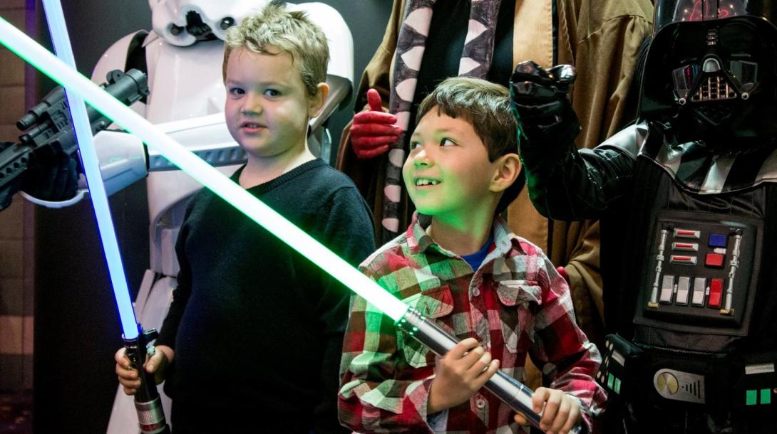 Photo of Children holding lightsabers and star wars cosplayers