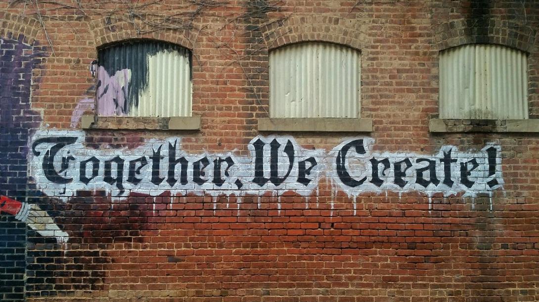 Together We Create spray painted on a brick wall