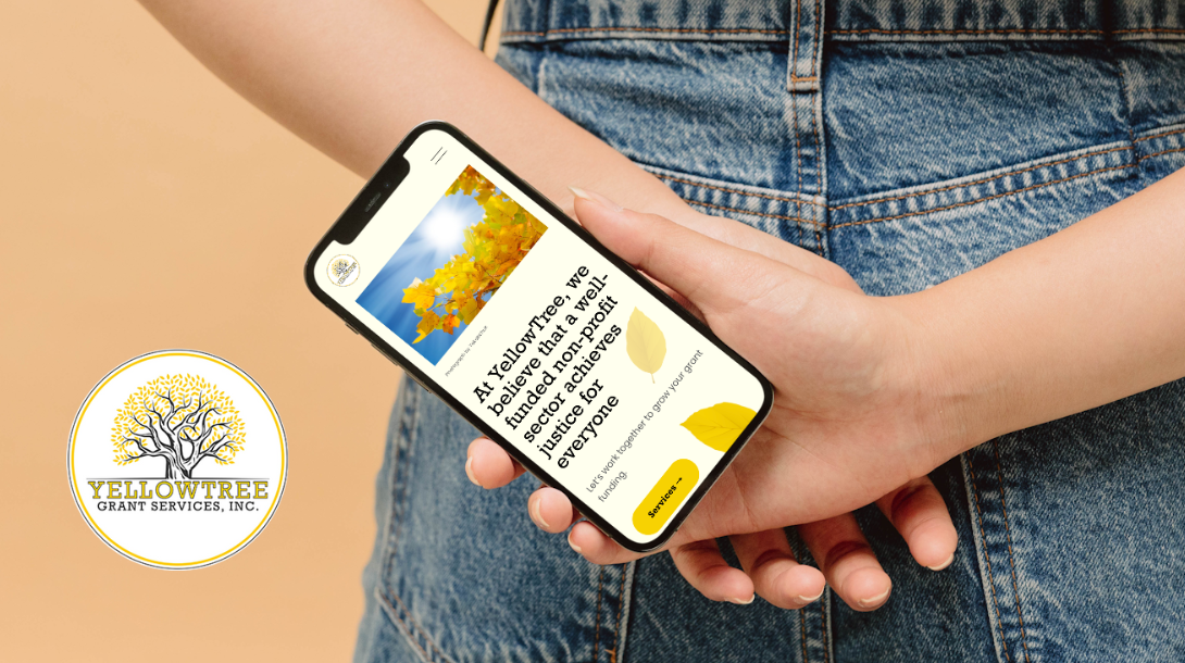 A person holding a phone that showcases the YellowTree Squarespace website on mobile.