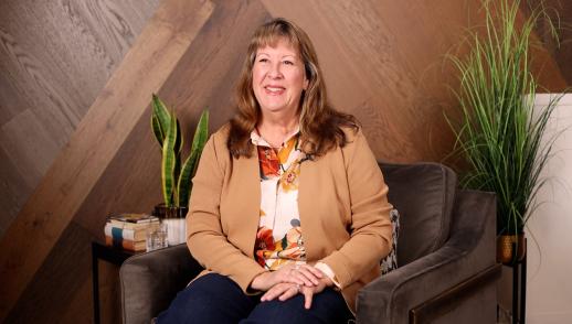The Chief Executive Officer of Humana sits upright smiling in a chair awaiting to be interviewed.