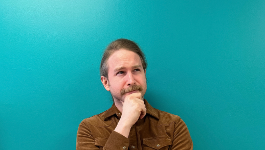 Designer Kevin in a thinker pose looking off to the right with a blue background.